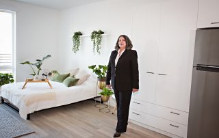 Women's Empowerment graduate in professional clothing, standing in a beautifully decorated apartment, one of the 19J midtown apartment units.