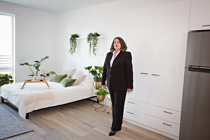 Women's Empowerment graduate in professional clothing, standing in a beautifully decorated apartment, one of the 19J midtown apartment units.