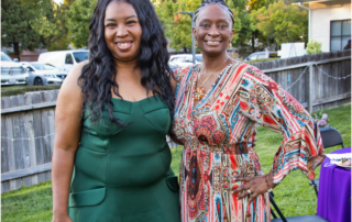 Two Women's Empowerment graduates, Natoshi and Robin, smiling and posing for the camera, in the backyard of Women's Empowerment, during the 2021 Grad Gala Celebration.